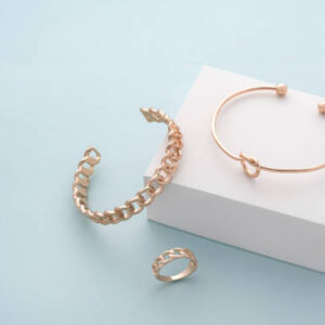 Modern golden bracelets and ring on white and blue back